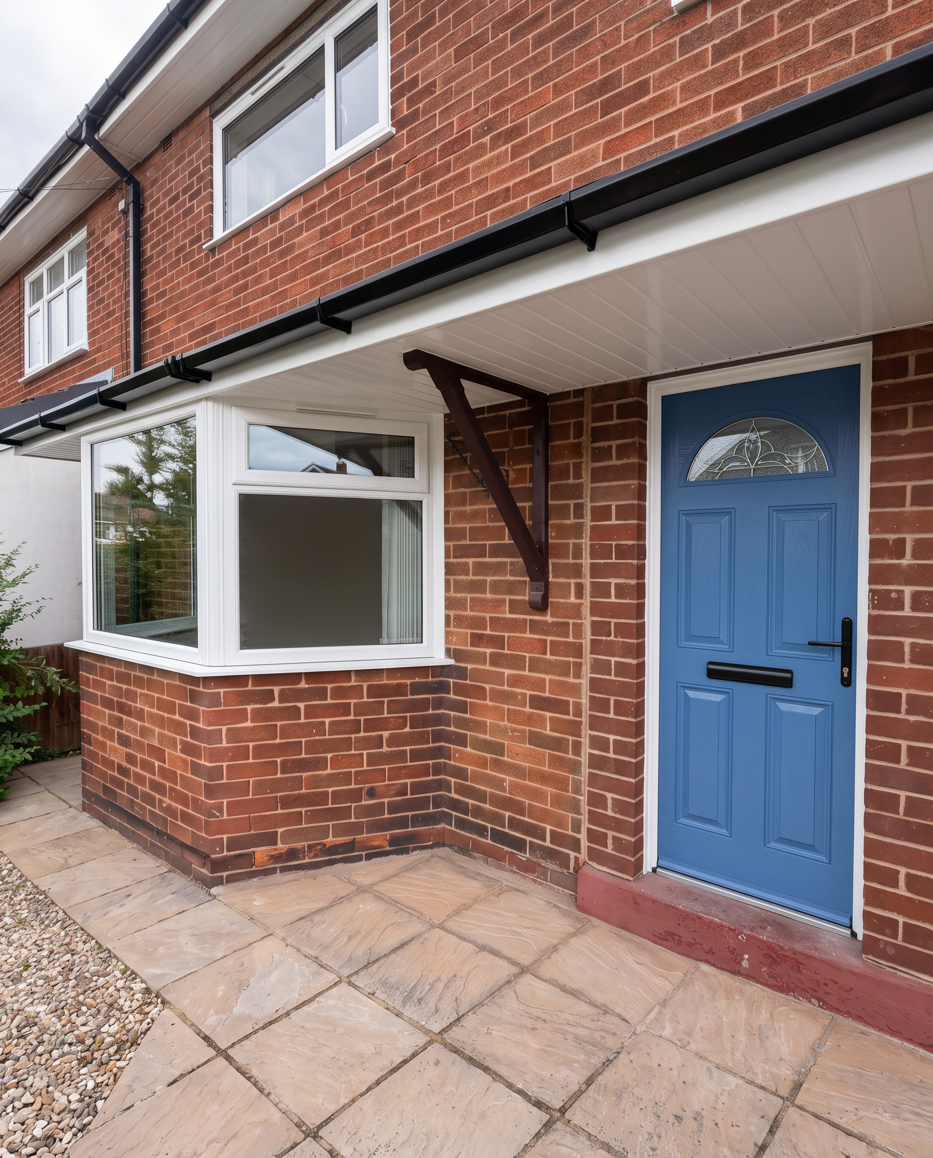 Blue composite front door with bay window on a red brick home